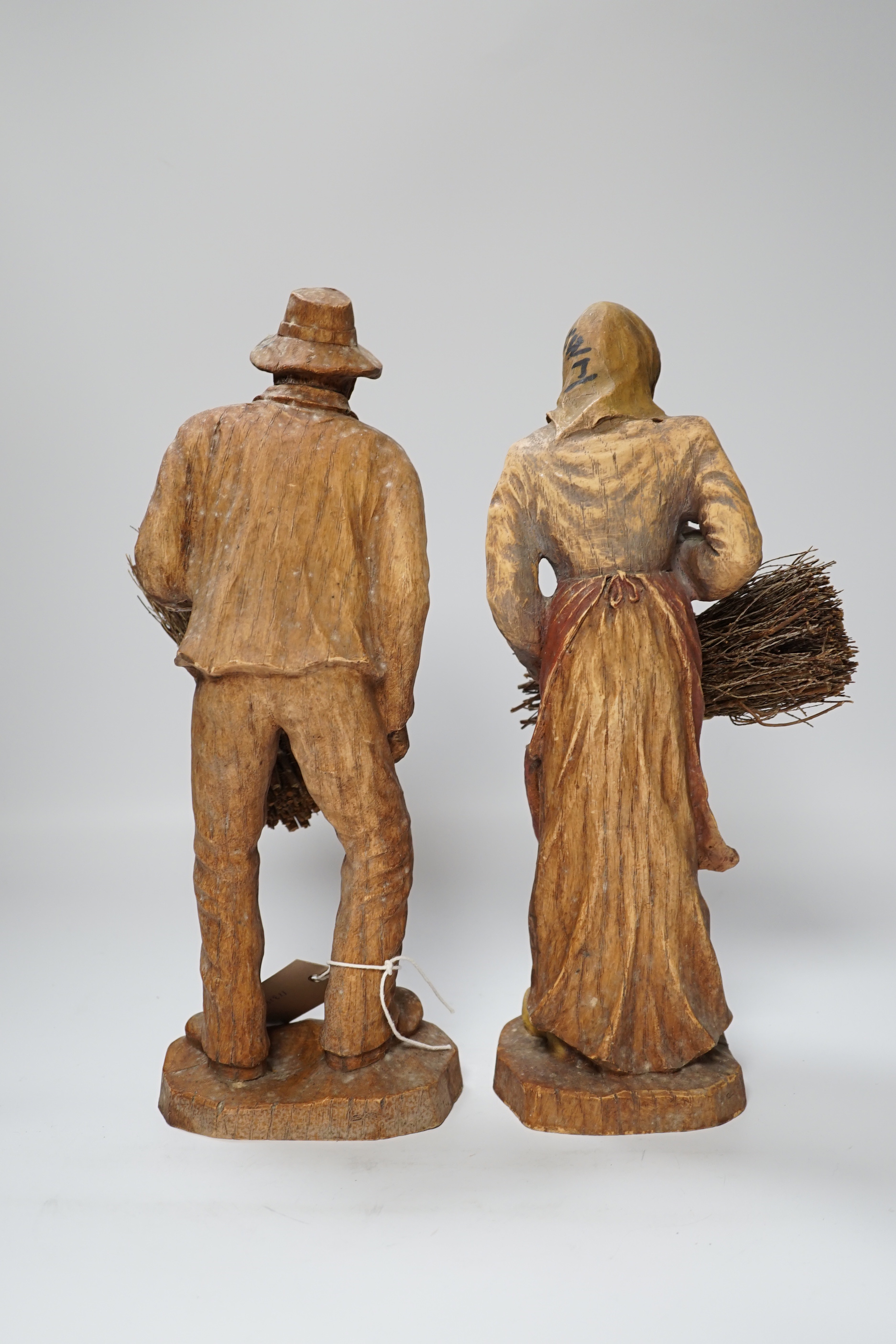 A pair of composition peasant figures gathering firewood, tallest 33cm